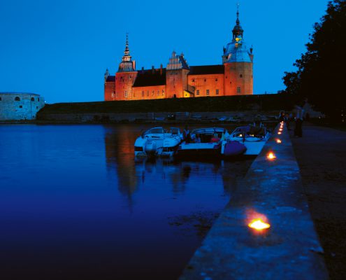 slott syns i skymningsljus och båthamn i förgrunden