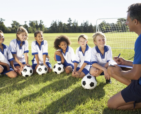 barn sittande på en fotbollsplan med vitblåa kläder